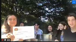 Screenshot of teenagers with a large novelty check.