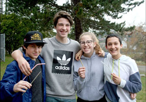 Four smiling teenagers holding drinking straws.