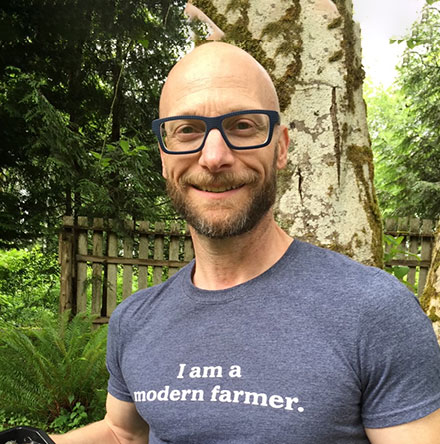 Image of smiling man in glasses wearing t-shirt that reads "I am a modern farmer."