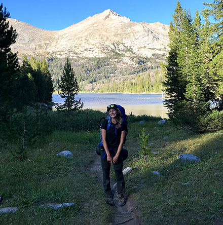 Young woman standing in front of mountain lake.