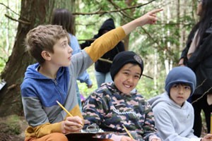 Two boys in the forest with clipboards.