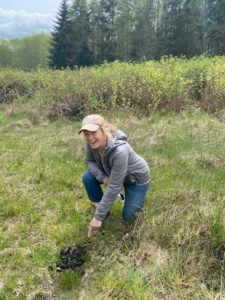 Woman posing next to large pile of bear scat