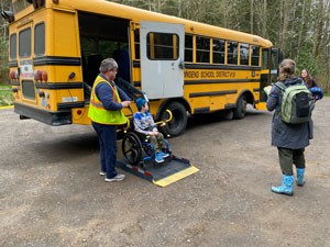 School bus with boy in wheelchair being lifted to ground