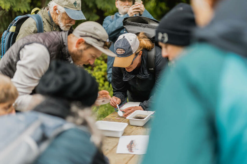 Group gathered around creek samples at picnic table outside.