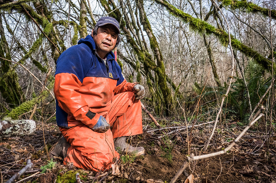 NEWnosc-trust-snow-creek-55 Japanese man in orange waders and rubber boots kneeling in forest clearing