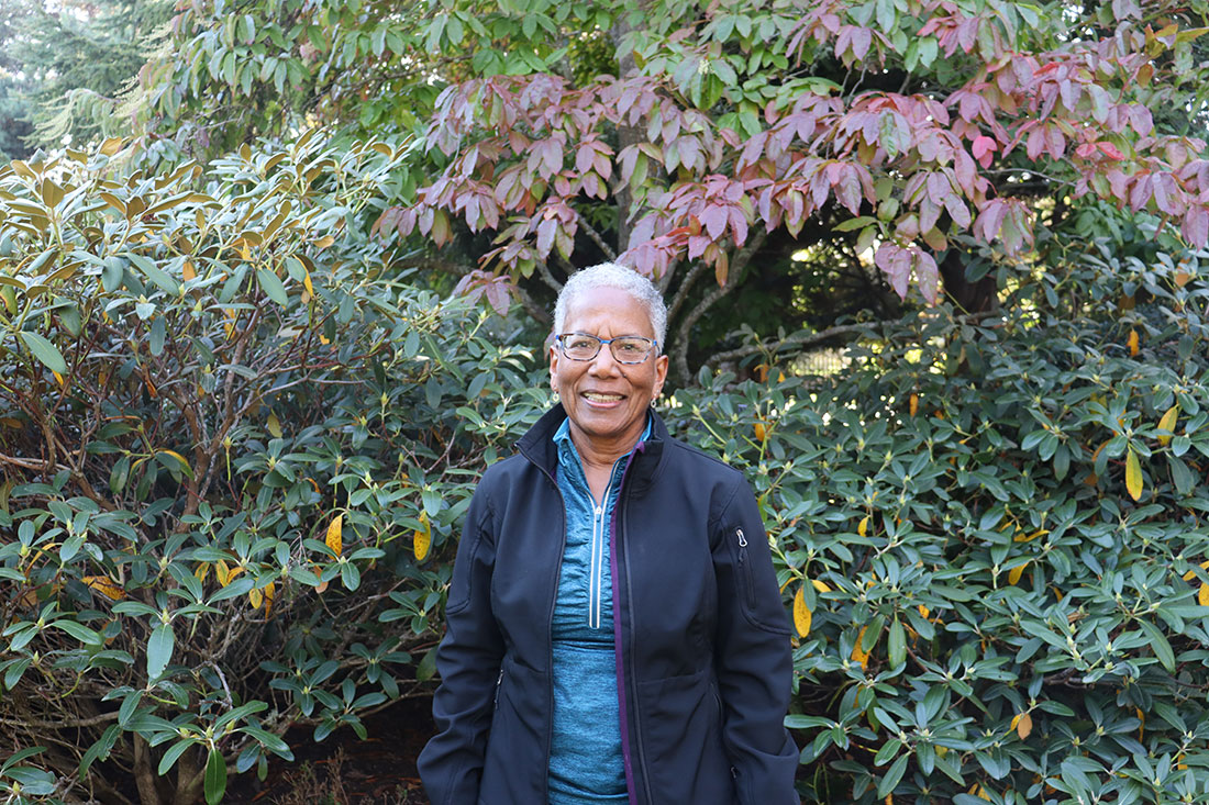 Smiling woman in front of shrubs