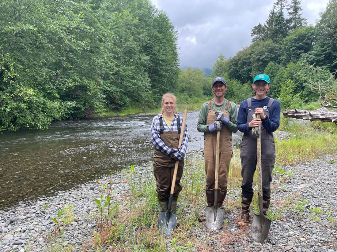 newlg4webIMG_9408 Three young people with shovels standing on riverbank