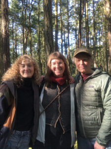 Photo of three women in front of a stand of trees.