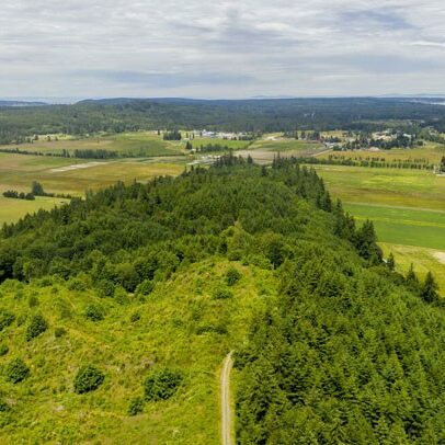 Photo of the tip of a forested ridge with farmland in the background.