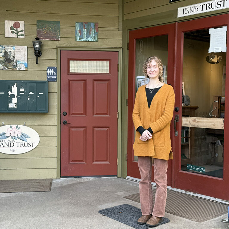 Photo of a woman standing in front of an office door.