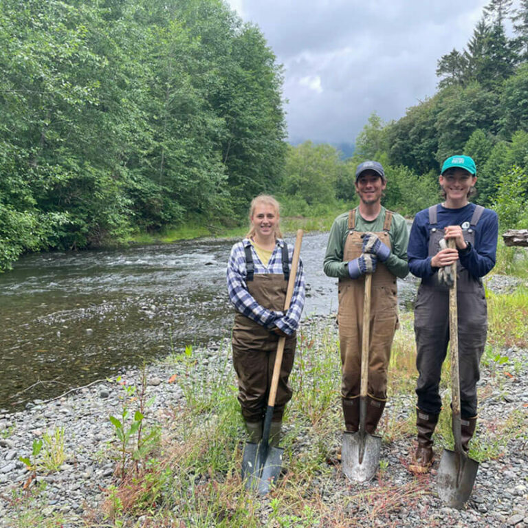 newlg4webIMG_9408 Three young people with shovels standing on riverbank